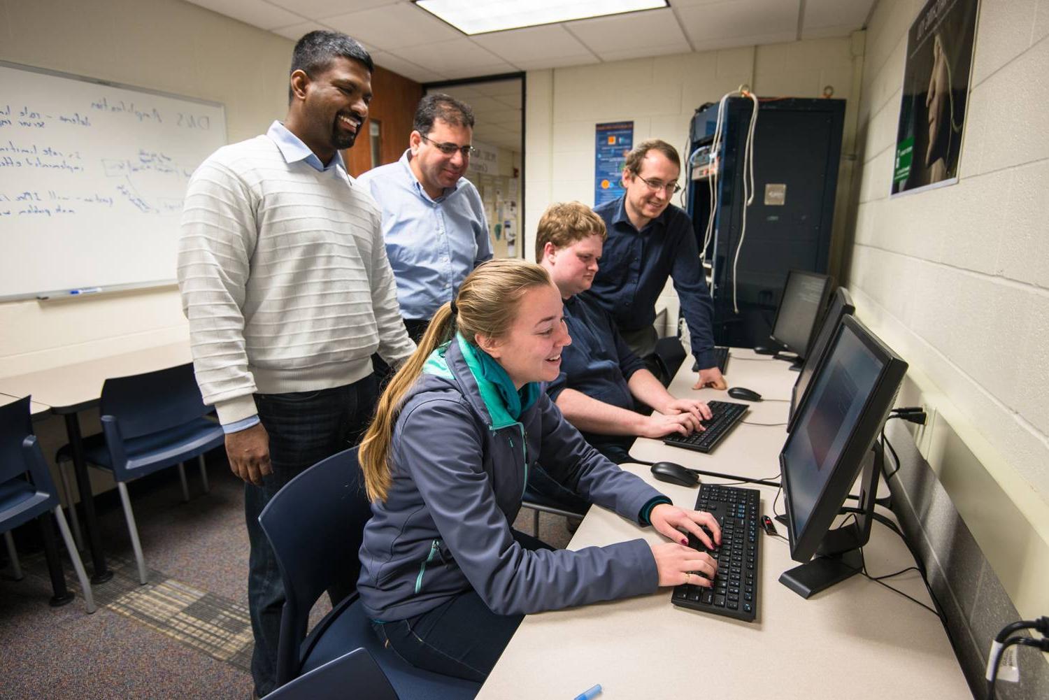 A group of faculty helping students in a research lab